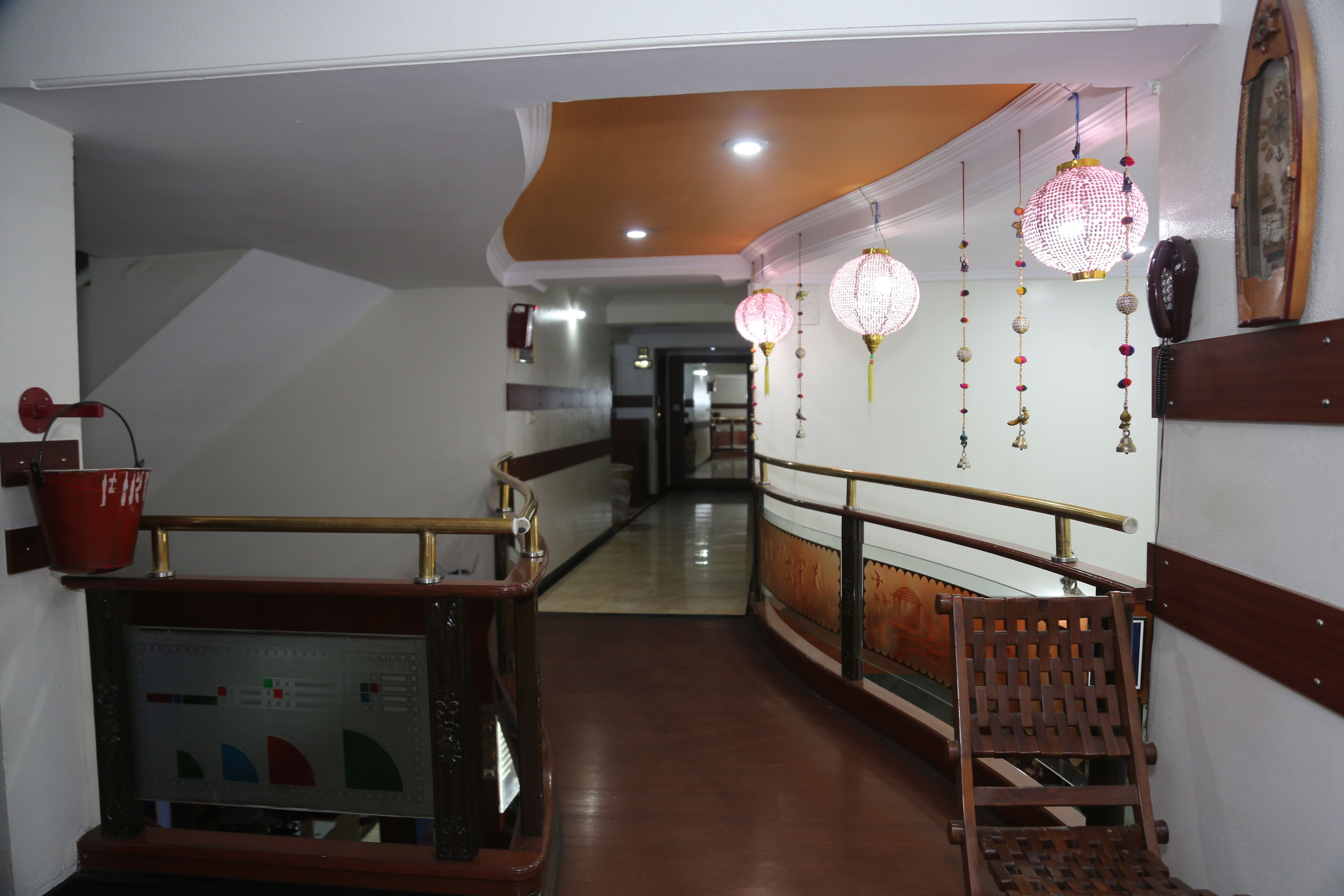 A hallway with a wooden bench, a red bucket, and decorative hanging lanterns.