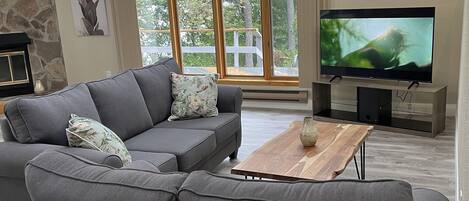 Una sala de estar moderna con un sofá modular, un televisor de pantalla plana y una chimenea de piedra.