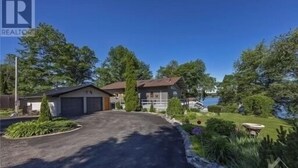 En bostadsfastighet med en uppfart som leder till ett garage, ett litet hus och en vackert anlagd trädgård med en damm.