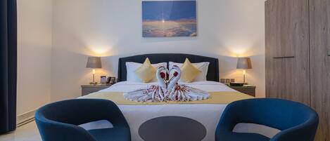 A modern hotel room with a large bed, two bedside lamps, a wall-mounted artwork, and a wooden wardrobe.