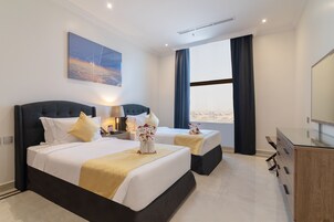 Habitación de hotel con dos camas, un ventanal grande, un televisor de pantalla plana y un aparador de madera.