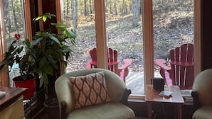 Una habitación acogedora con un gran ventanal, techo de madera y un ciervo montado.