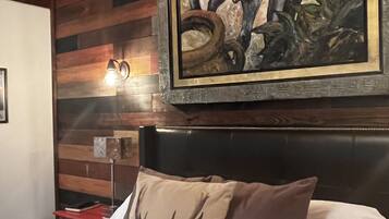 Un dormitorio con una cama, un cuadro grande de un jinete y un caballo, y una pared de madera.