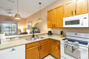 Una cocina con armarios de madera, microondas, lavavajillas y ventilador de techo.