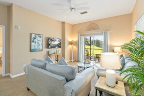 A living room with a grey sofa, a coffee table, a lamp, and a painting on the wall.