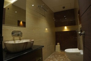 A modern bathroom with a large vessel sink, a toilet, and a shower area. - The Pride (Golmuri)