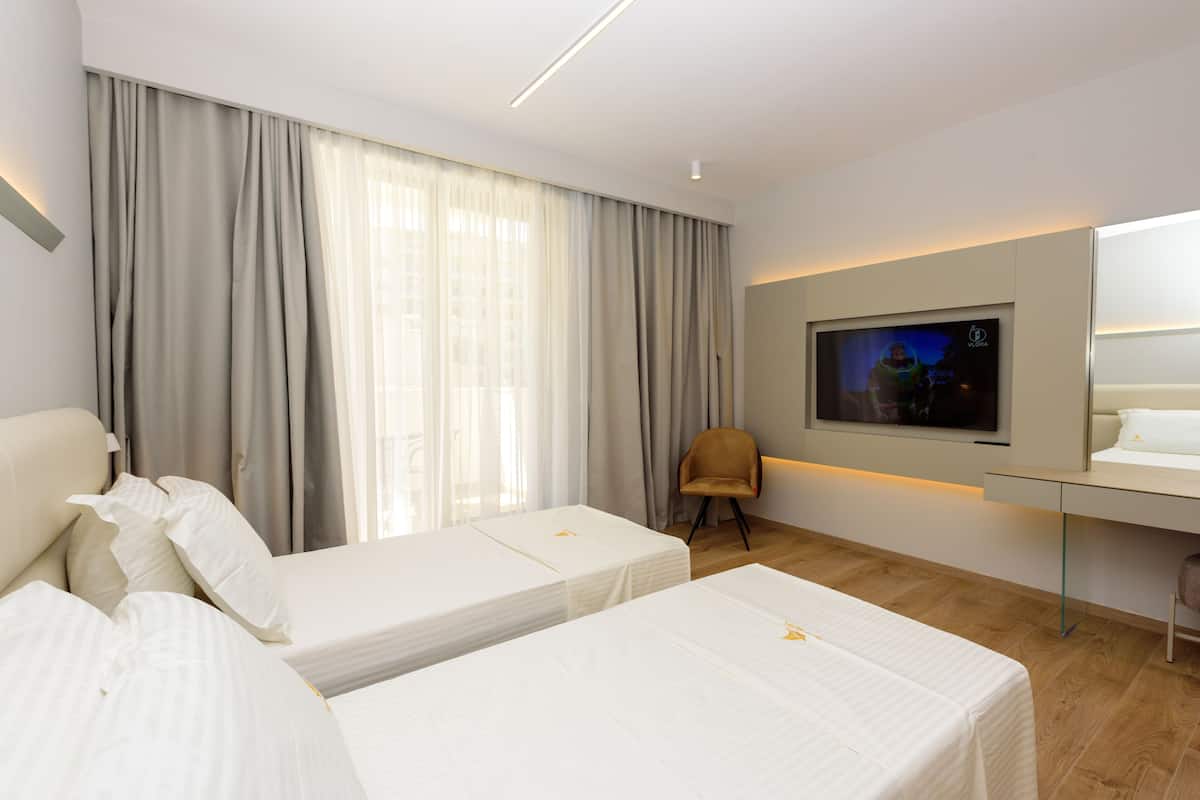 Une chambre d’hôtel avec deux lits, une télévision, une chaise et un bureau.
