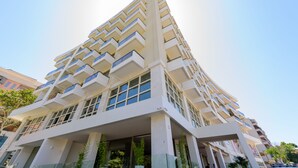 Un edificio moderno de varios pisos con una fachada geométrica distintiva, ventanas amplias y balcones.