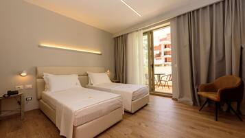 A hotel room with two beds, a desk, and a chair.