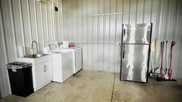 A compact kitchen with a stainless steel refrigerator, a washing machine, and a sink.