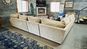 A cozy living room with a sectional sofa, a fireplace, and wooden walls. - New Rustic Retreat, Firepit & Games, Hiking, Boating & Fishing near Lake Rathbun (Moravia)