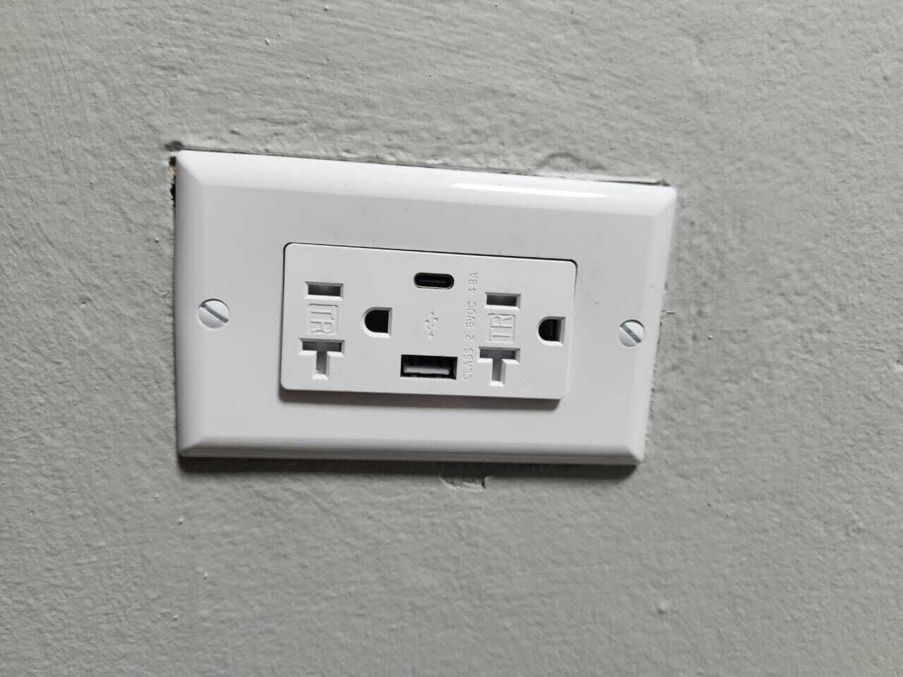 A white electrical outlet on a textured wall.