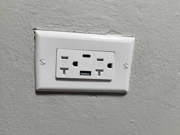 Une prise électrique blanche sur un mur à texture.