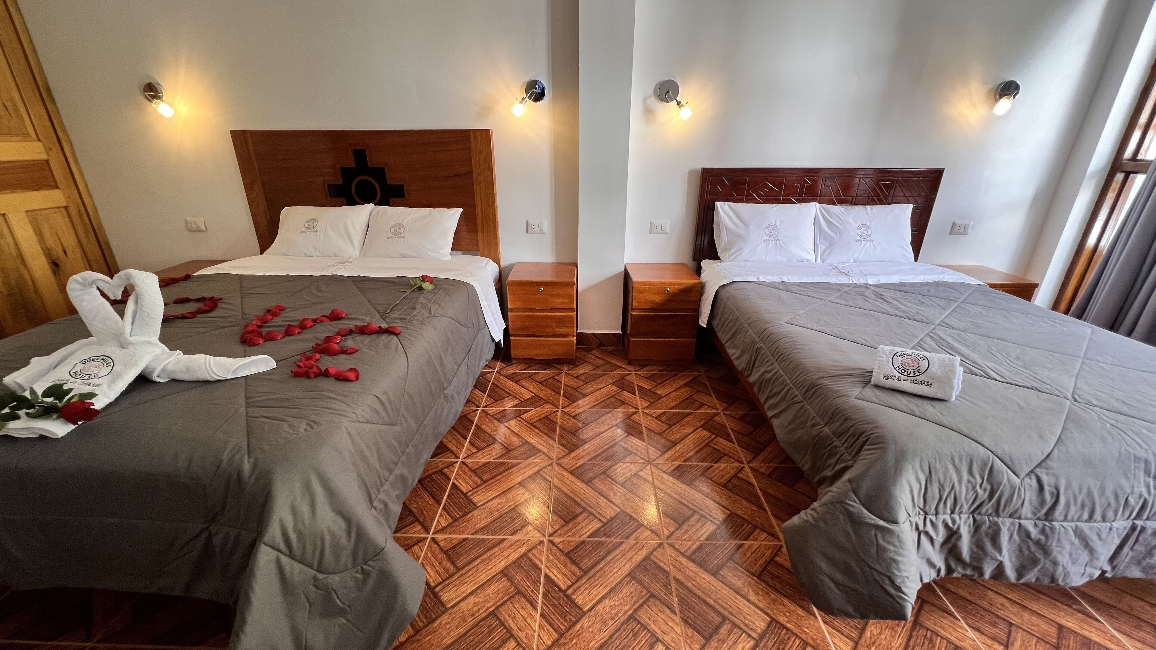 Two adjacent hotel rooms with wooden headboards, matching nightstands, and a herringbone-patterned wooden floor.