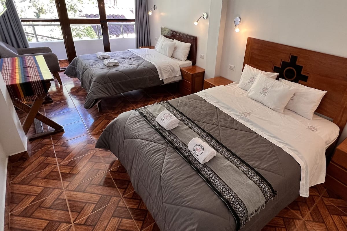 A hotel room with two beds, wooden headboards, and a herringbone-patterned floor.