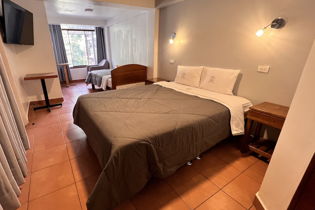 A bedroom with a bed, a desk, and a chair.