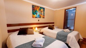 Une chambre d’hôtel avec deux lits, un tableau au mur et une porte donnant sur une salle de bain.