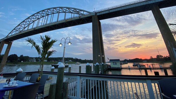A waterfront restaurant with outdoor seating overlooking a river, a bridge, and a sunset. - Chesapeake City Quiet Overlook (Chesapeake City)
