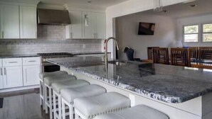 A modern kitchen with white cabinets, a granite countertop, and a stainless steel range hood. - Chesapeake City Quiet Overlook (Chesapeake City)