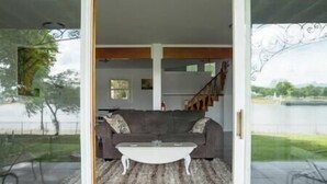 A living room with a sofa, coffee table, and a view of a lake through a glass door. - Chesapeake City Quiet Overlook (Chesapeake City)