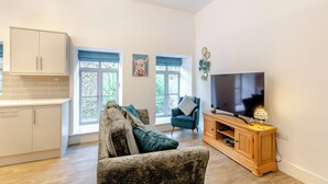 A modern living room with a sofa, a television, and a wooden cabinet. - 1 bedroom accommodation in Haworth (Haworth)