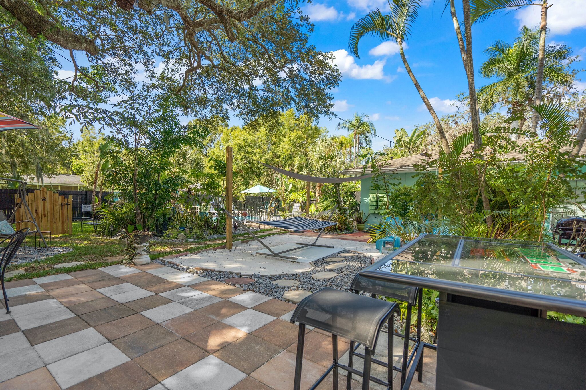 A patio area with a checkered floor, outdoor seating, and a hammock.