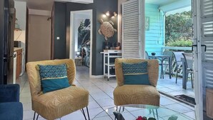 Un salon comprenant deux fauteuils, une table basse et un coin repas avec une table et des chaises.