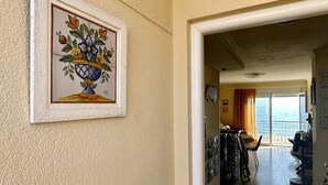 A hallway with a framed floral artwork on the wall, leading to a dining area with a view of the sea. - Sea Beach House (Oliva)