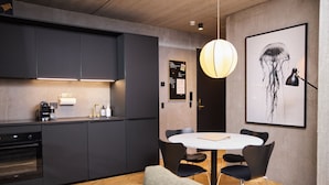 Una cocina moderna con armarios oscuros, horno empotrado y comedor con mesa y sillas redondas.