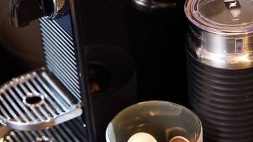 Uma máquina de café, uma garrafa térmica e um recipiente com cápsulas de café.