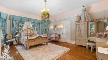 A bedroom with a four-poster bed, a dresser, a vanity, and a chair.