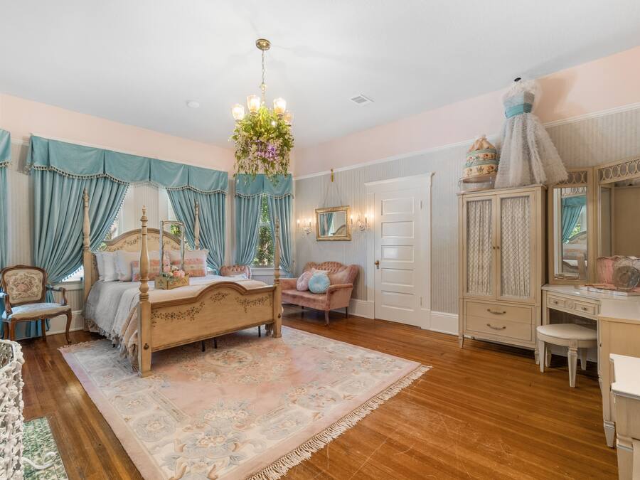 A bedroom with a four-poster bed, a dresser, a vanity, and a chair.