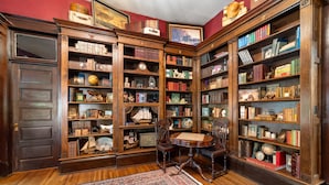 Une bibliothèque traditionnelle avec des étagères en bois, une table ronde et des chaises.