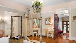 Une chambre à coucher avec un lit à baldaquin, une commode, une coiffeuse et un lustre.