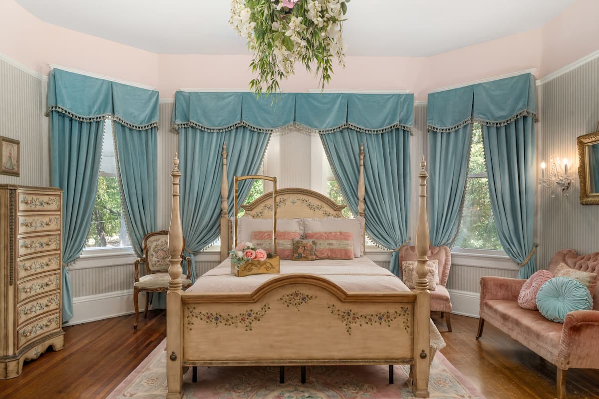 Une chambre à coucher avec un lit à baldaquin, une commode, une chaise et un canapé.