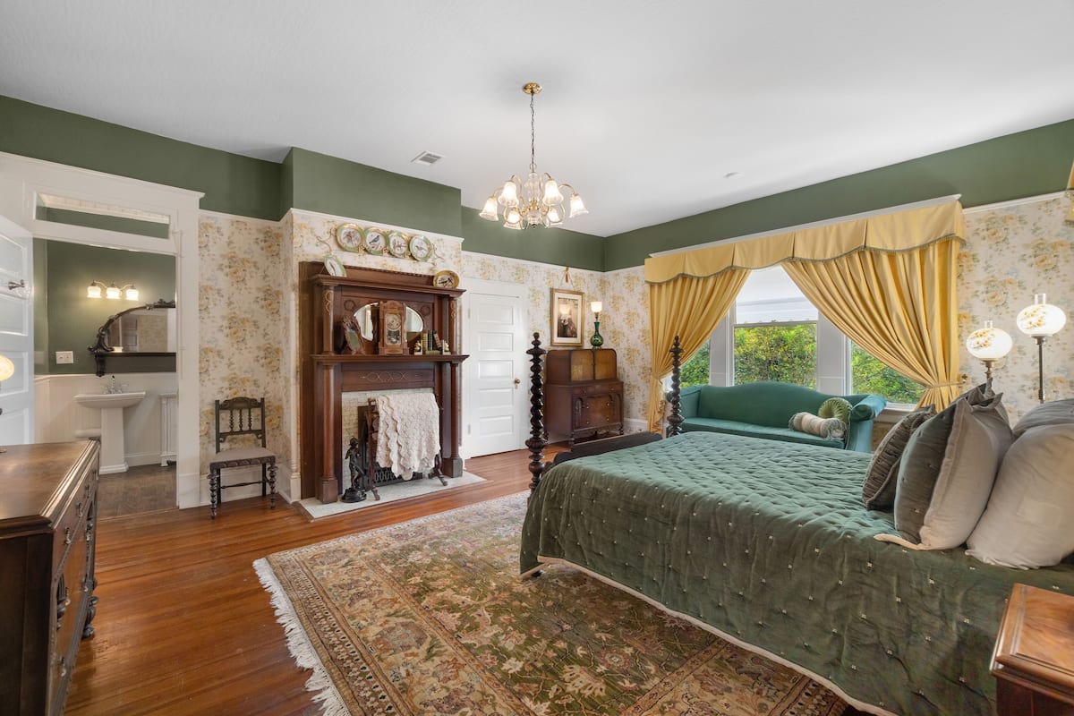 Une chambre à coucher avec un grand lit, une commode, une coiffeuse, un miroir et un lustre.