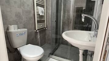 A bathroom with a toilet, a shower enclosure, and a sink.