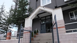 A building with a staircase leading to a door, a gated entrance, and a small tree in a pot. - Konak Suite Ankara (Ankara)