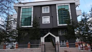 Un edificio moderno de dos pisos con amplios ventanales, una escalera central y una entrada con portón.