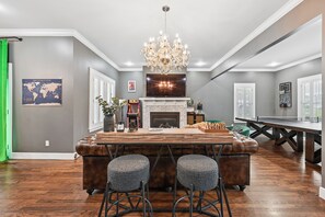 A spacious living area with a fireplace, a large TV, and a bar area with stools.