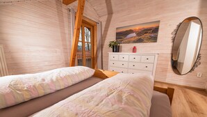 A cozy bedroom with two beds, a dresser, a mirror, and a painting of a sunset landscape. - Neu Renovierte Ferienwohnung in Zentraler Ruhiger Lage (Lenggries)