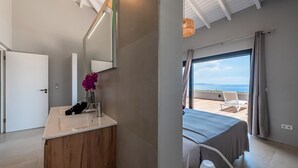 Un dormitorio moderno con un ventanal grande, una cama y vista al mar.