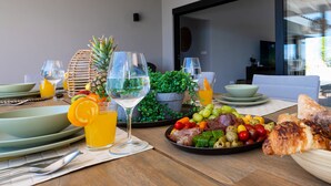 Una mesa de comedor servida con platos, vasos y una variedad de alimentos, incluyendo frutas, verduras y carnes.