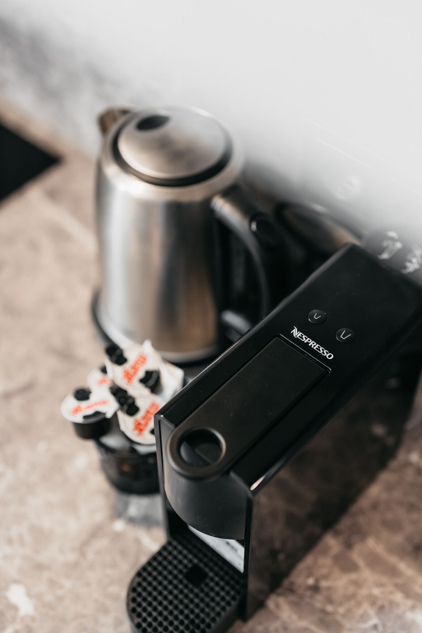 A coffee machine with a pod dispenser and a stainless steel kettle.