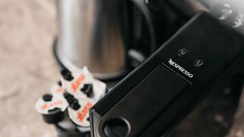 A coffee machine with a pod dispenser and a stainless steel kettle.