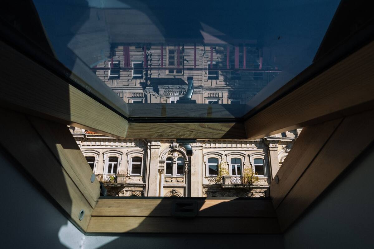 A view from a skylight of a building with classical architecture, including arched windows and detailed stonework.