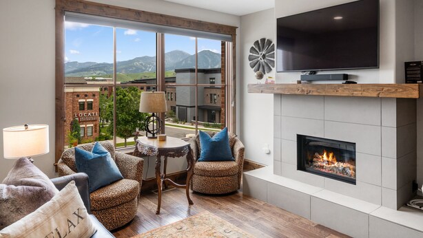 Un salón amplio con un gran ventanal, una chimenea, un televisor de pantalla plana y una mesa con sillas.