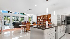 A modern kitchen with a central island, built-in appliances, and a dining area with a view of the outdoors. - Waterfront Oasis - Saltwater Pool - Kayaks - Minutes to Fort Lauderdale Beach! (Fort Lauderdale)