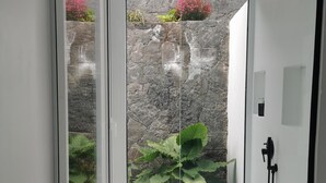 Ein Zimmer mit Blick auf eine Steinmauer und Pflanzen hinter einer Glasdoor.