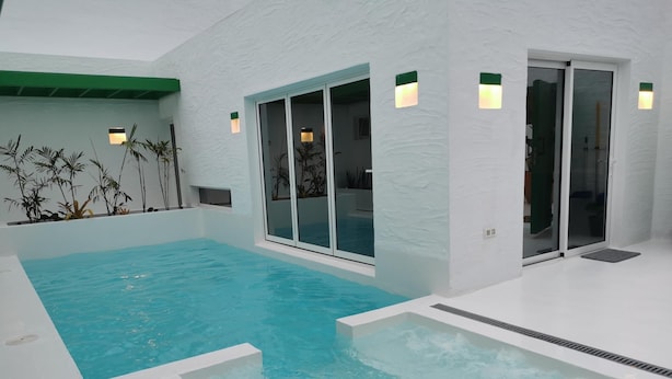 Ein Hallenbad mit klarem Wasser, umgeben von weißen Wänden und einer grünen Decke.